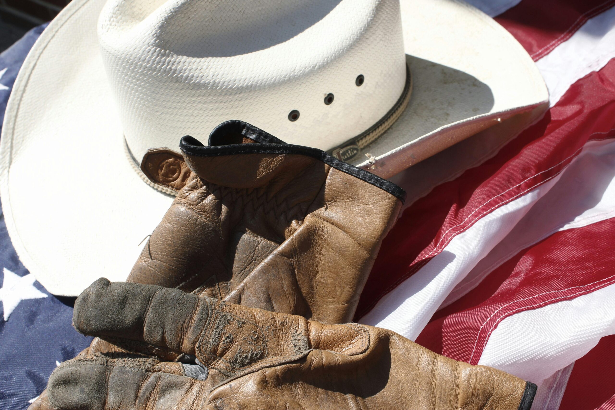 Home Close-up of a cowboy hat and gloves on an American flag.